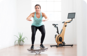 A woman balancing on a balance board in front of an exercise bike