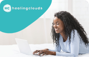 A woman smiling while typing on her laptop, with the words healingclouds in a blue bubble above her