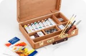 A wooden box containing a multitude of paints and paint brushes
