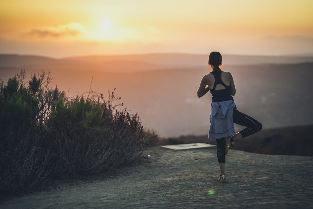 Person practicing yoga at sunrise
